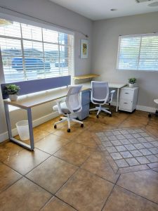 Private office showing two desks with chairs and exterior windows.